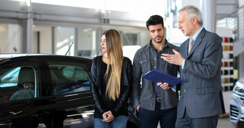 wedding car rental explaining a car's features to a couple by reading a document