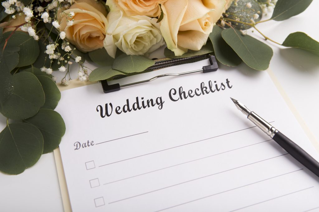 Empty Wedding checklist with creative pen and roses on white table in bride room, copy space for text