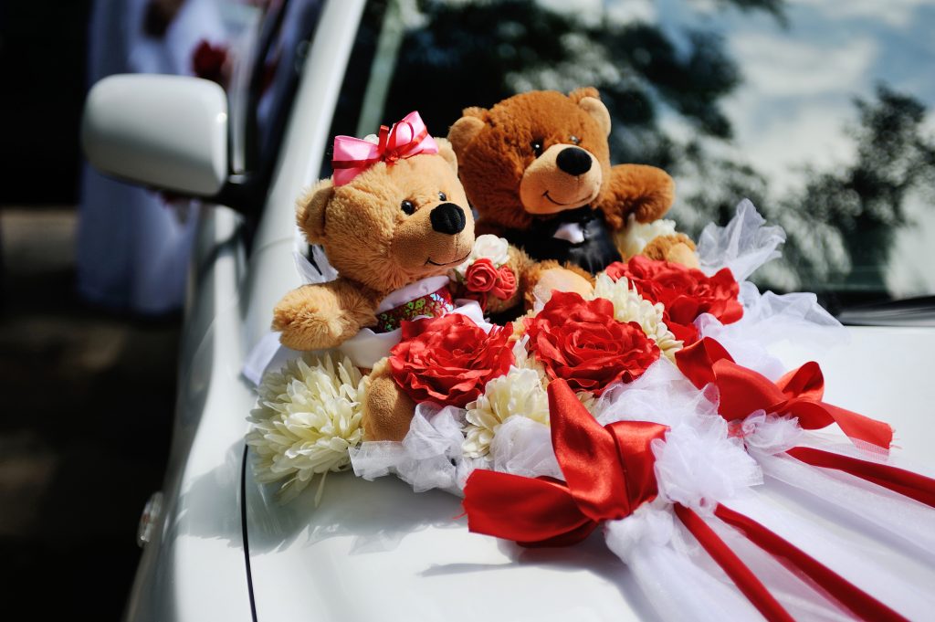 Two toy bear on the hood of wedding car. Toy bears dressed in Costa groom and bride's dress. Wedding decor